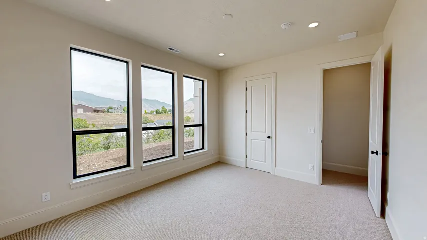 Room featuring three tall windows with black frames, offering expansive outdoor scenery
