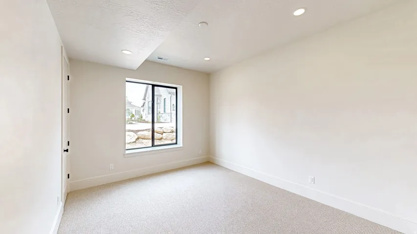 Bright room with neutral carpeting, recessed lighting, and a large egress window