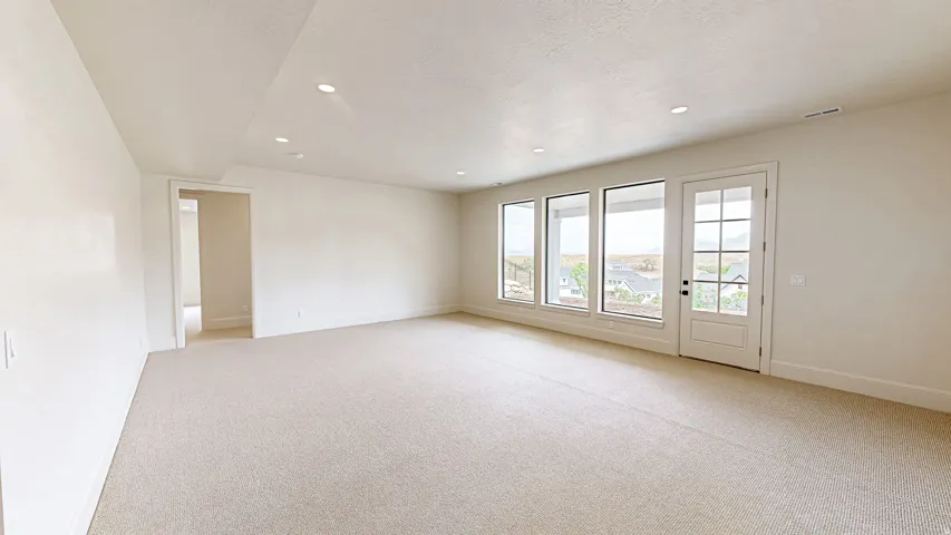 Spacious interior room with light-toned carpeting and recessed ceiling lighting