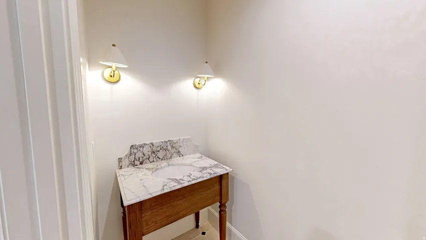 Vanity featuring a patterned stone countertop with an integrated sink and a wood-finish base