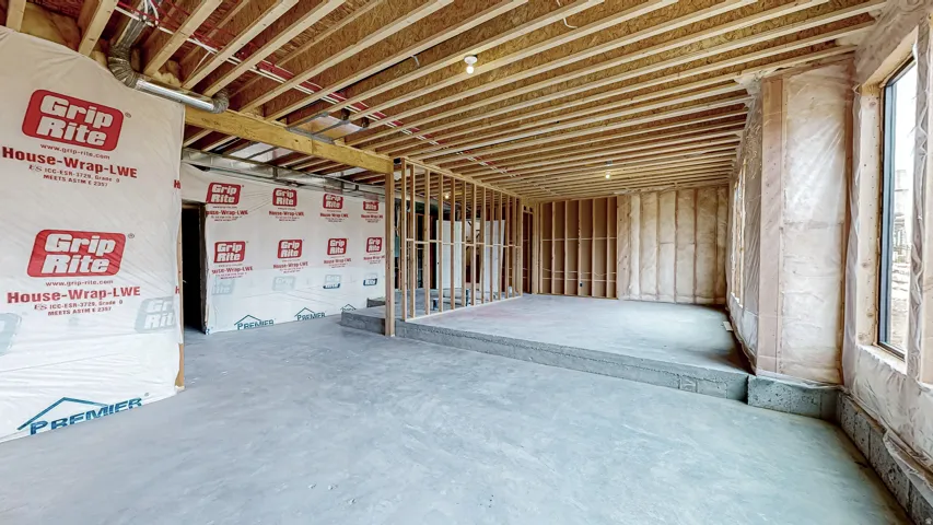 Unfinished basement featuring exposed wood framing, concrete flooring, and multiple windows allowing for natural illumination