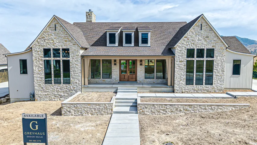 Stone-clad exterior featuring a prominent gable, dormer windows, and a covered porch