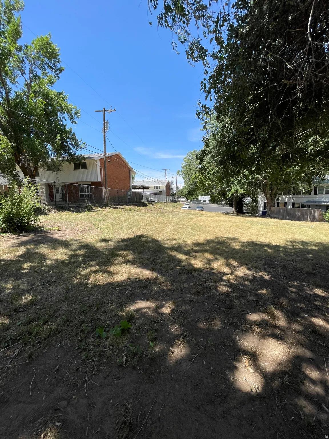 Expansive clear lot offering a substantial building envelope, featuring partial grass ground cover and mature perimeter trees
