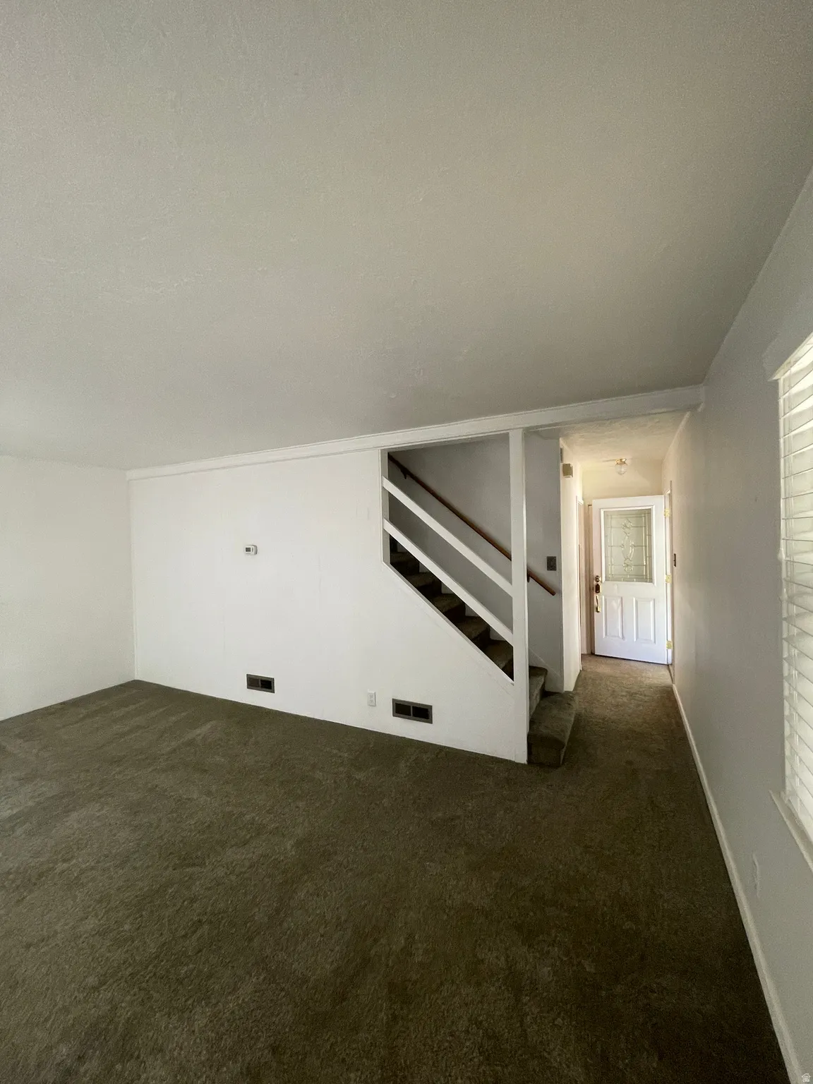 Carpeted living space with white walls and baseboards