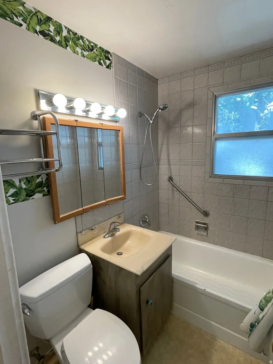Bathroom featuring a tub/shower combination with a hand-held showerhead and a safety grab bar