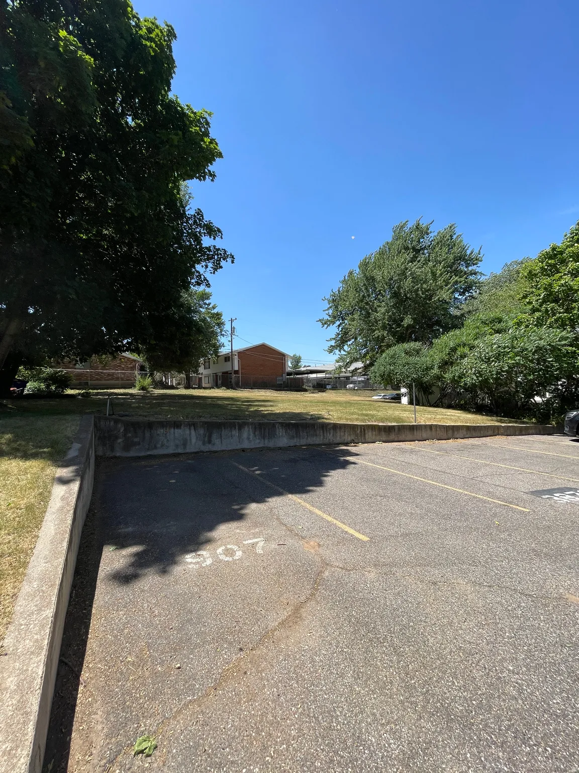 Paved parking area with marked spaces and an adjacent concrete retaining wall