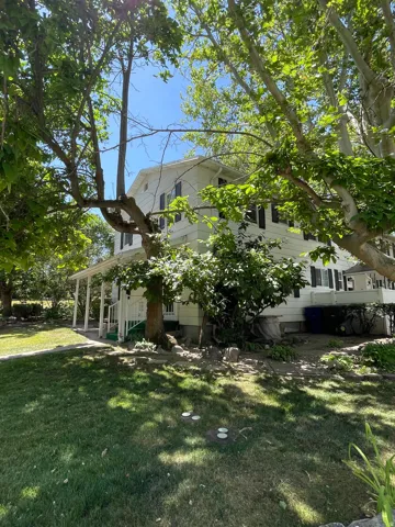 Two-story residence featuring a covered porch, white siding, and dark window shutters