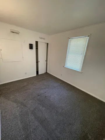 Room featuring dark gray carpet flooring, white walls, and a window with blinds