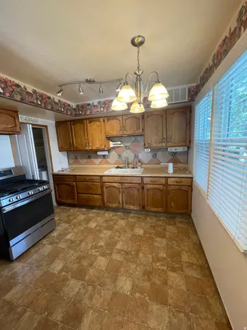 Kitchen featuring wood cabinetry, laminate countertops, a stainless steel range, and tile flooring