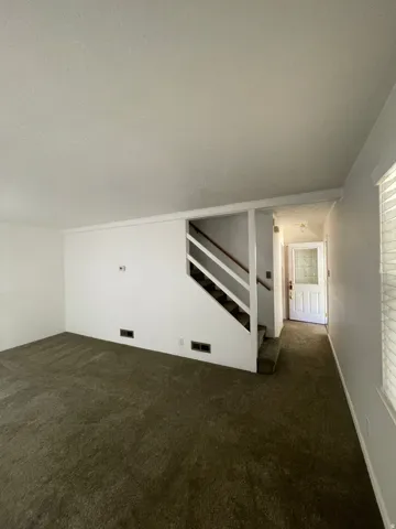 Carpeted living space with white walls and baseboards