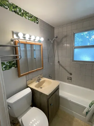 Bathroom featuring a tub/shower combination with a hand-held showerhead and a safety grab bar