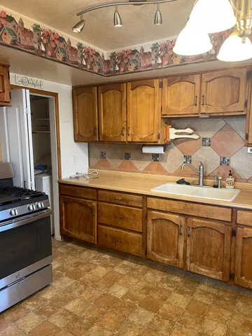 Kitchen featuring wood cabinetry, laminate countertops, a tile backsplash, and checkered floor tiles