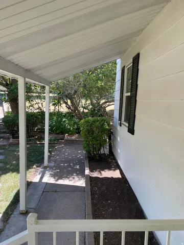 Covered porch with white siding exterior and black louvered shutters