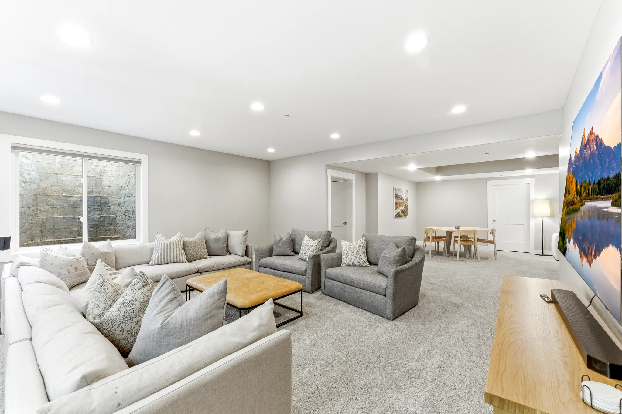 Spacious lower-level living area with recessed lighting and neutral carpet flooring