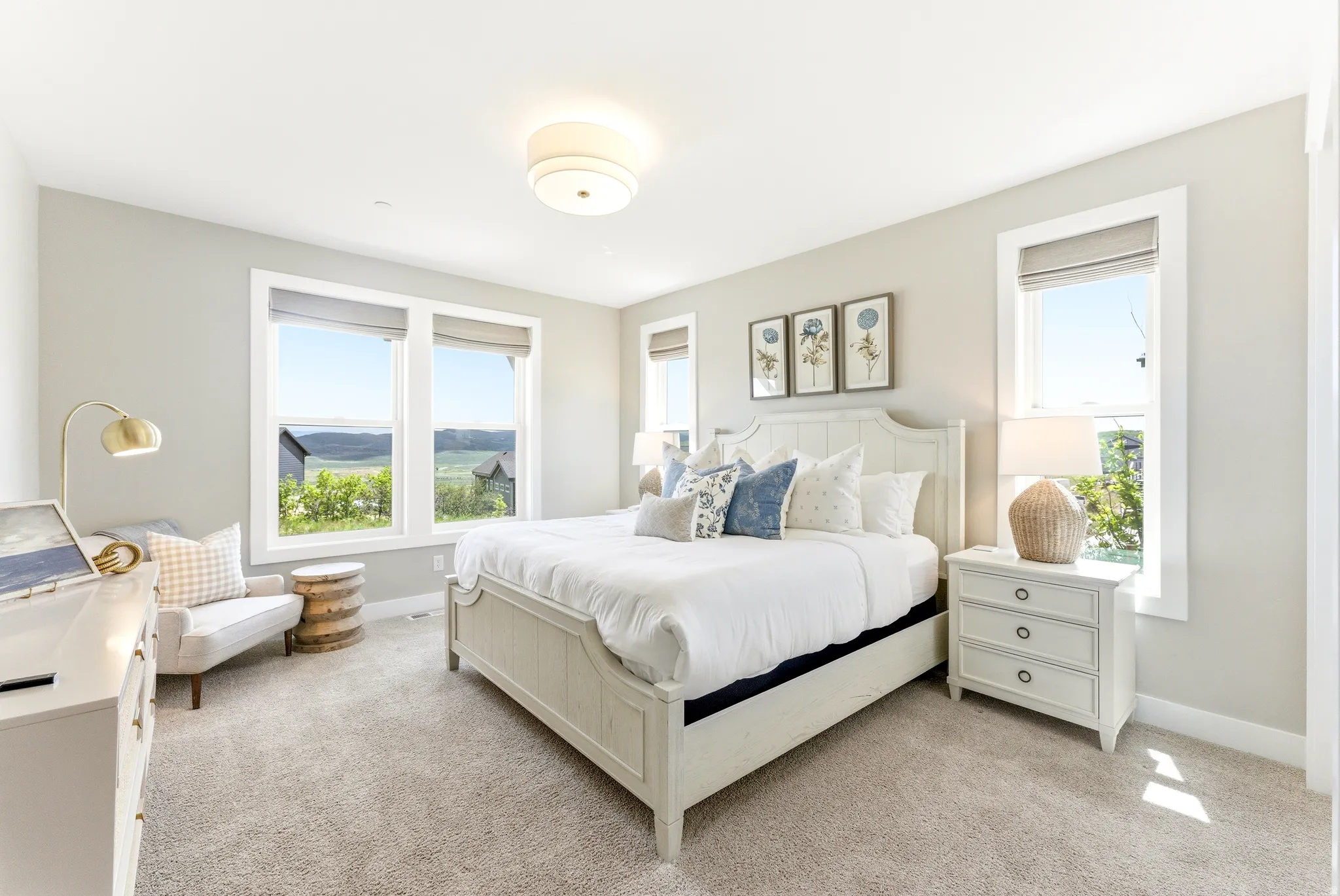 Spacious room featuring multiple windows with natural scenery, light neutral wall paint, and soft carpeting