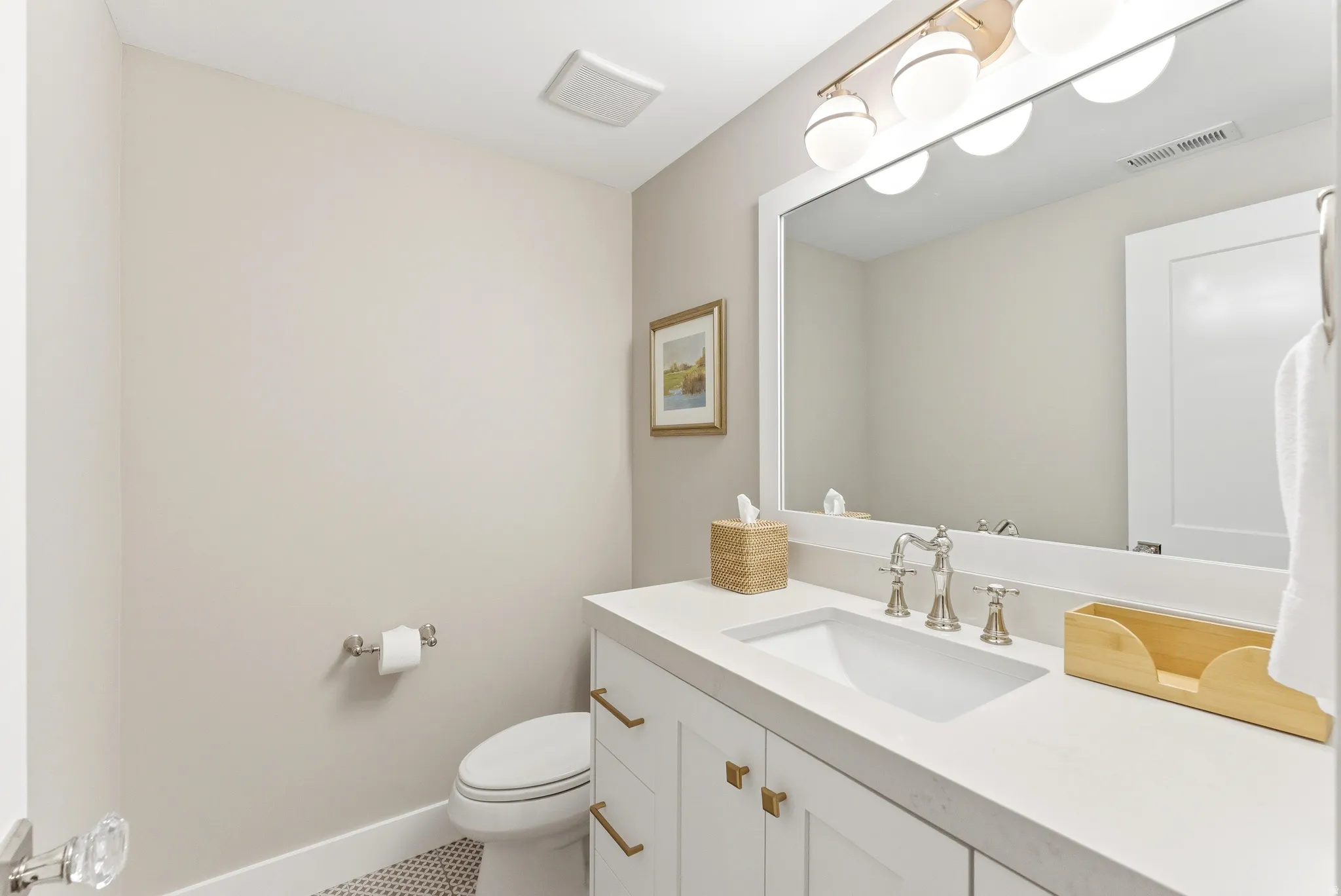 Contemporary bathroom featuring a white vanity with gold-finish hardware, a large mirror, and an integrated sink with a polished nickel faucet