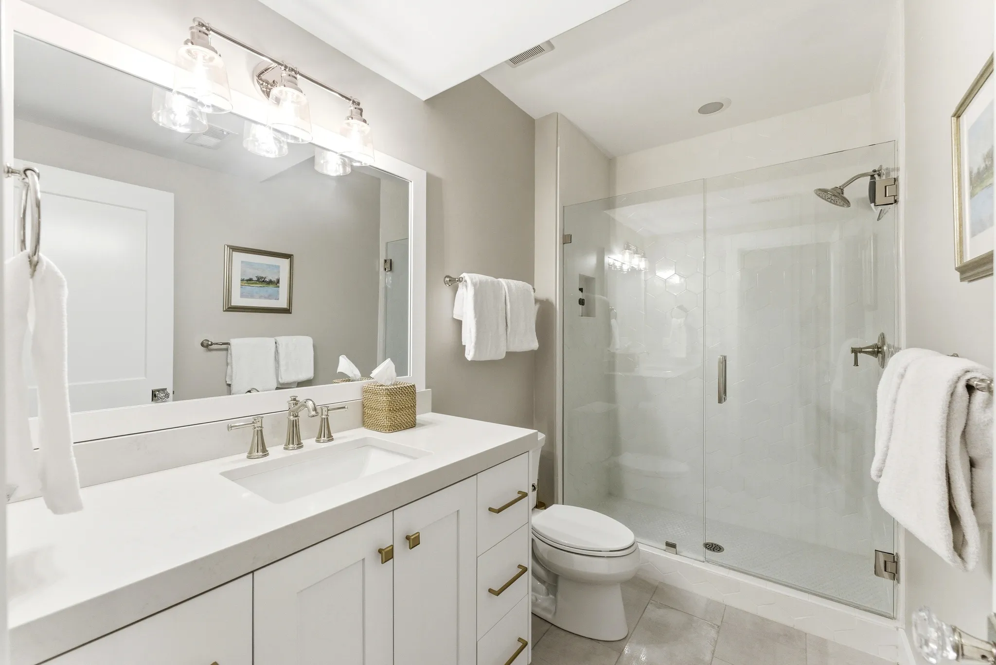 Modern bathroom featuring a frameless glass shower enclosure, a vanity with white cabinetry, brushed nickel hardware, and a single basin
