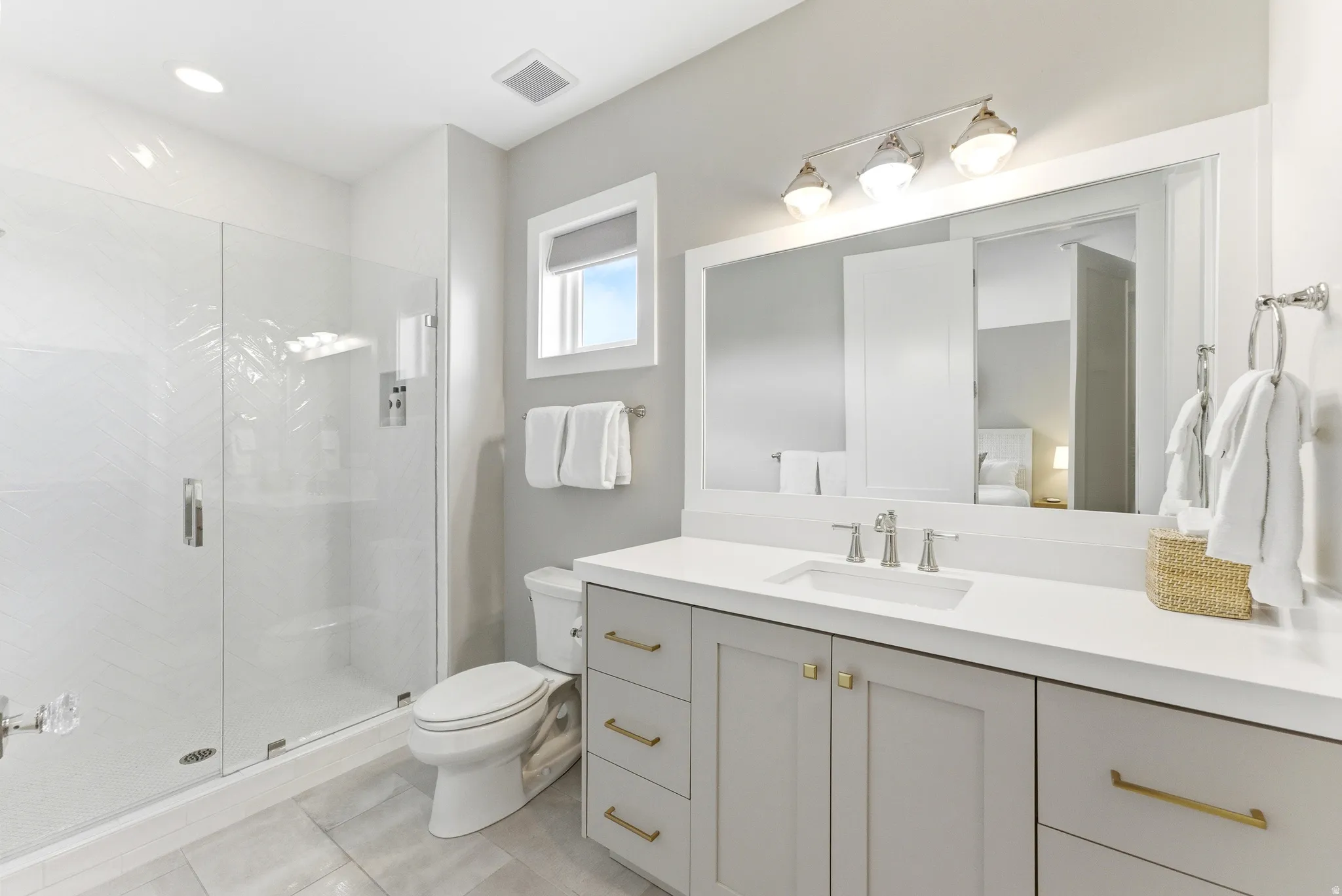 Bathroom featuring a glass-enclosed shower, single-basin vanity with light gray cabinetry, white countertop, and a vanity mirror with overhead lighting