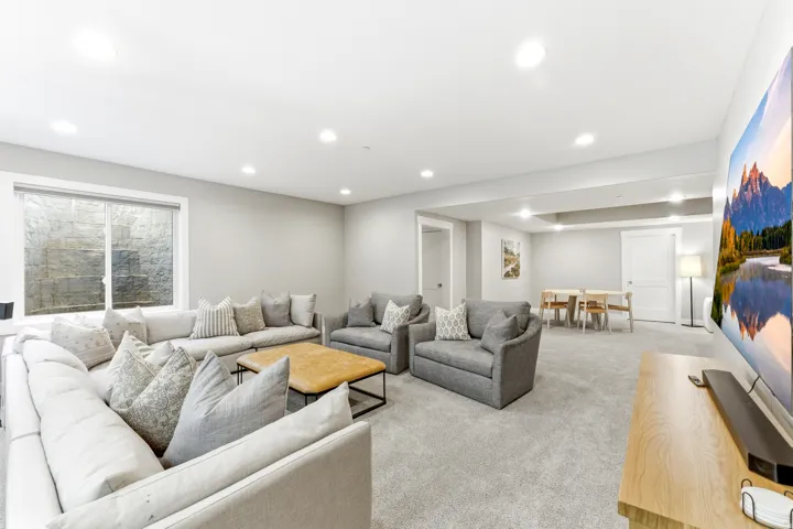 Spacious lower-level living area with recessed lighting and neutral carpet flooring