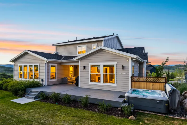 Rear elevation featuring a multi-level concrete patio, integrated hot tub, and a covered outdoor living area