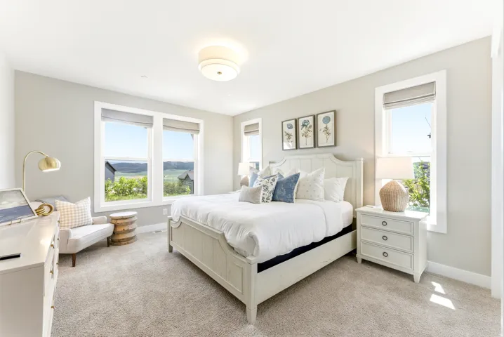 Spacious room featuring multiple windows with natural scenery, light neutral wall paint, and soft carpeting
