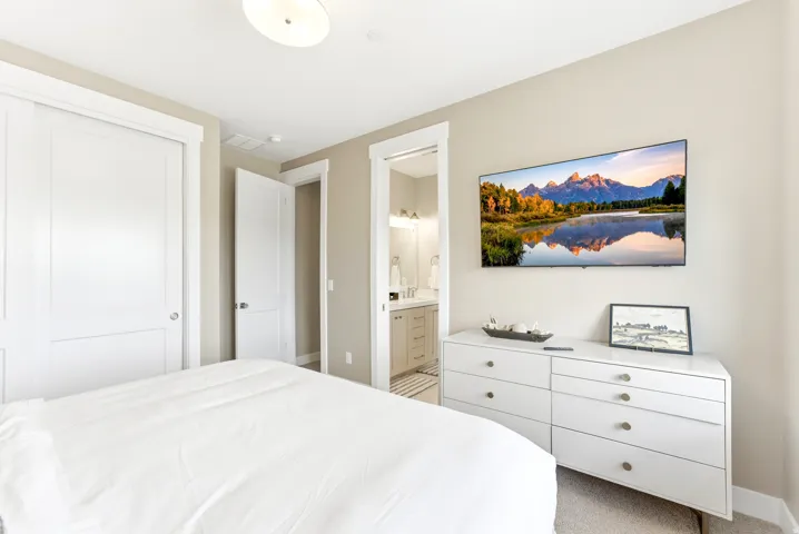 Recessed lighting illuminates a space featuring light neutral walls and light-toned carpet
