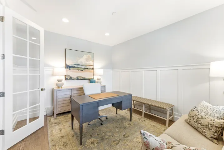 French doors with glass lites, wood-finish flooring, recessed ceiling lighting, and wainscoting details characterize this interior space