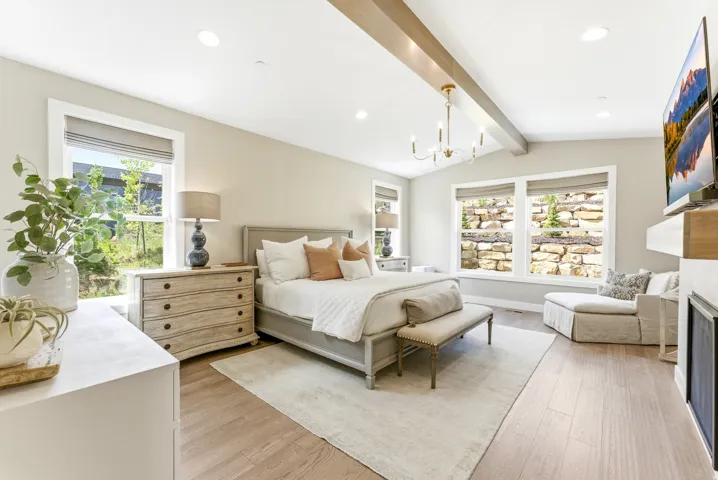 Spacious room featuring vaulted ceilings with exposed wood beams, a modern chandelier, and recessed lighting