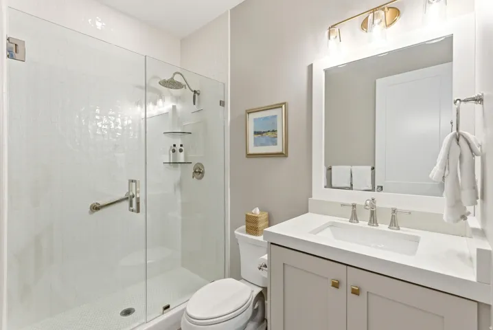 Contemporary bathroom featuring a frameless glass shower enclosure with white textured tile surround and a rain showerhead
