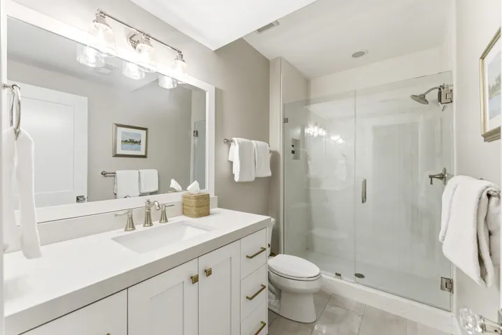 Modern bathroom featuring a frameless glass shower enclosure, a vanity with white cabinetry, brushed nickel hardware, and a single basin