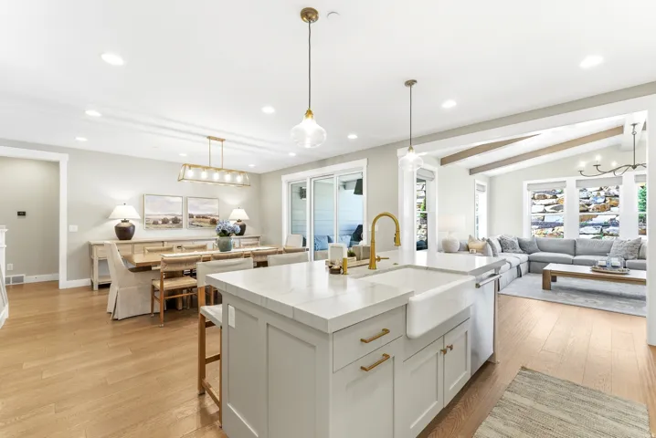 Kitchen island featuring a farmhouse sink and brass-finish faucet, complemented by wood-finish flooring