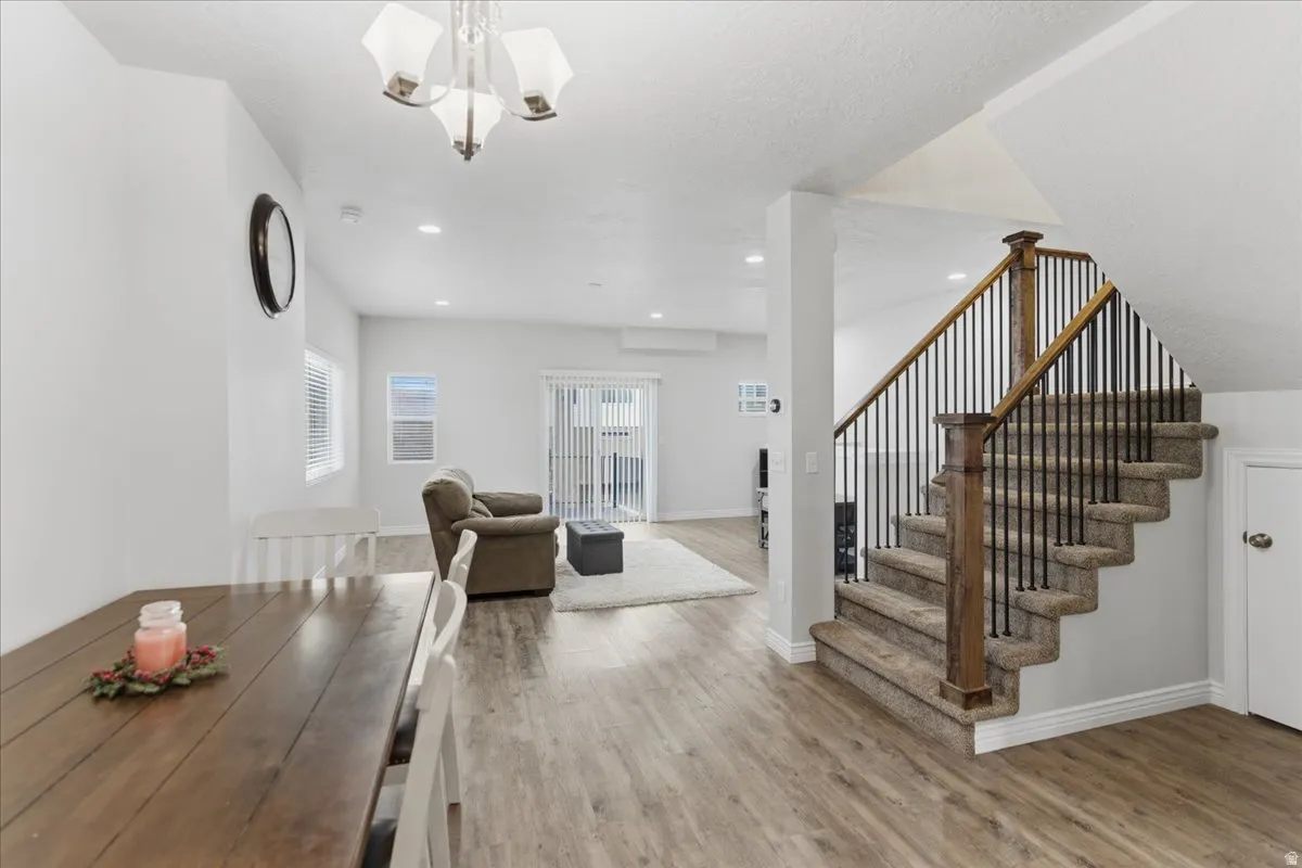 Open-concept living space featuring wood-finish flooring, recessed lighting, and a staircase with a wood banister and iron spindles