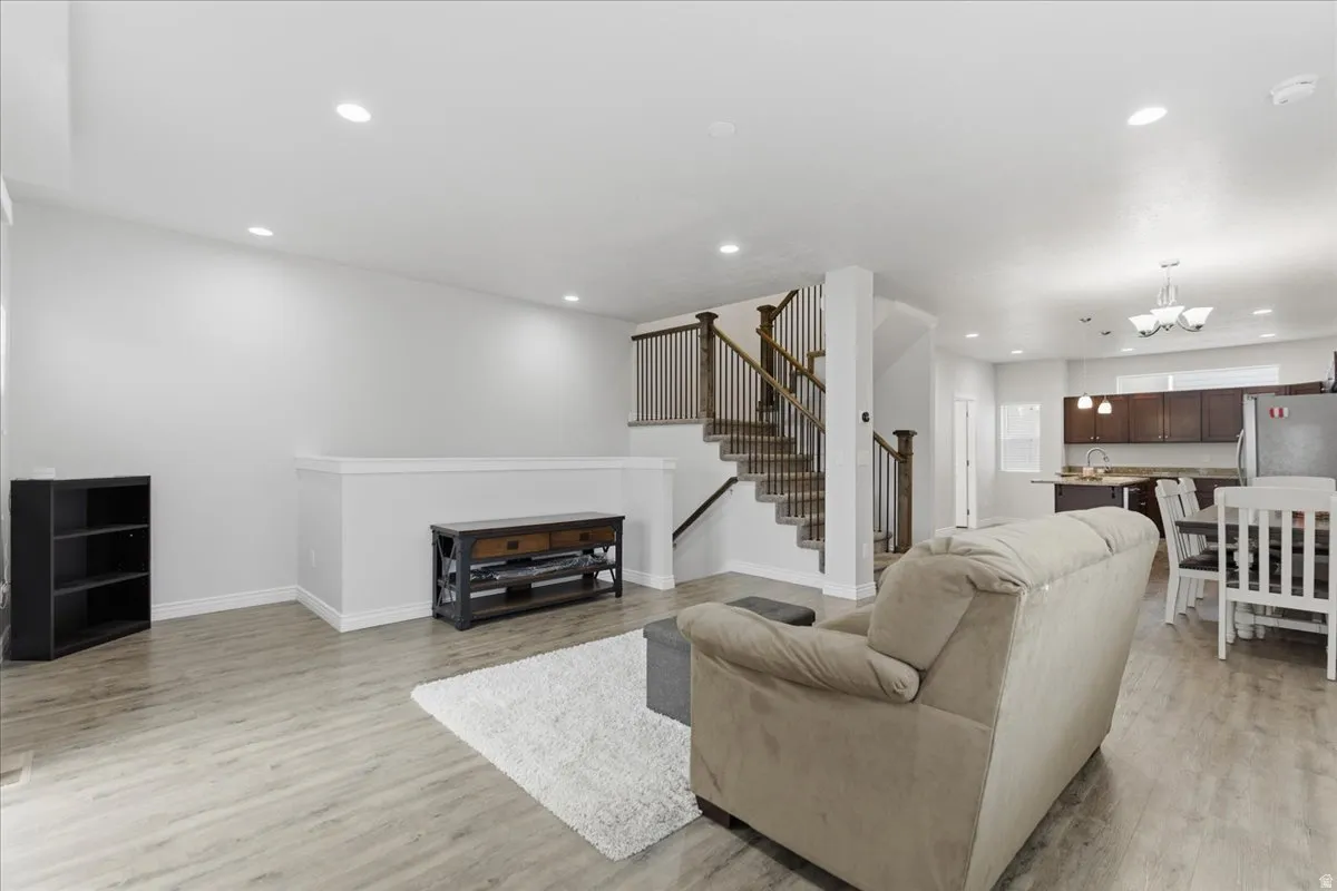 Open-concept living area featuring wood-finish flooring, recessed lighting, and a staircase with wood newel posts and metal balusters