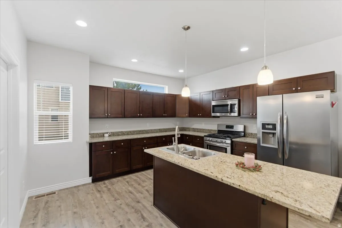 Kitchen featuring wood-finish flooring, dark wood cabinetry, and light-toned countertops