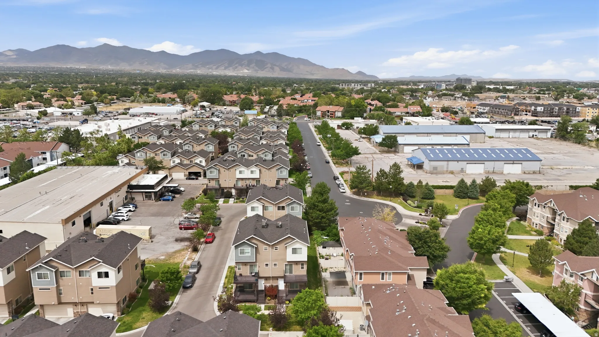 Aerial perspective showcasing a residential community featuring multi-story townhomes with garages and balconies