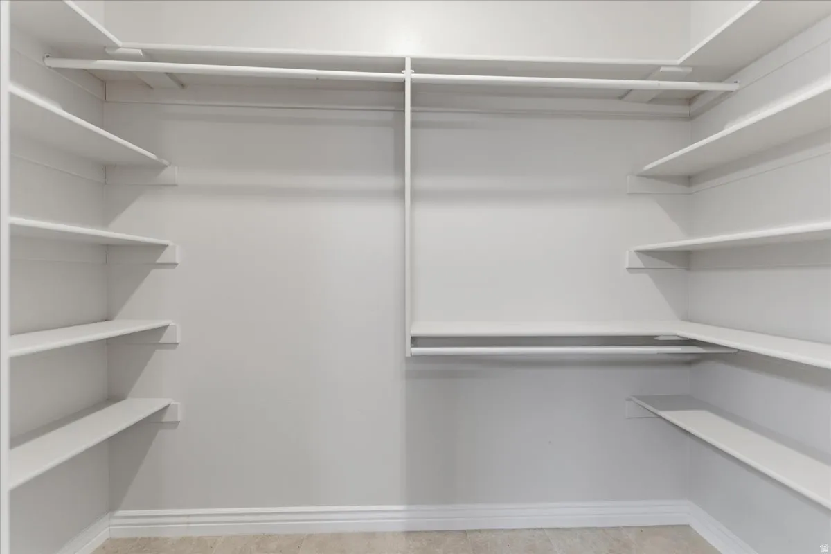 White-painted closet featuring multiple shelving units and clothing rods
