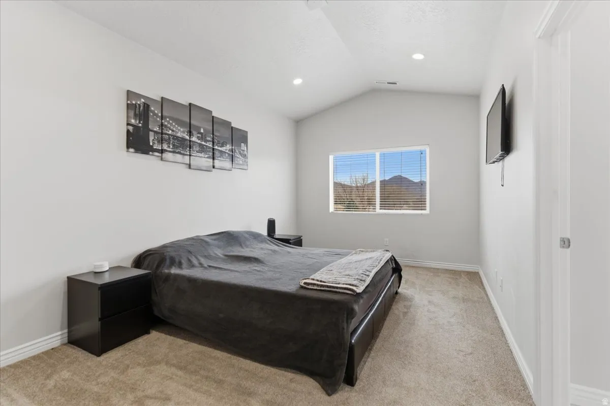 Carpeted interior space featuring a vaulted ceiling and recessed lighting