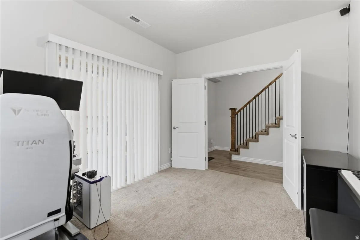 Carpeted room with double doors opening to a staircase with wood-finish railing and risers