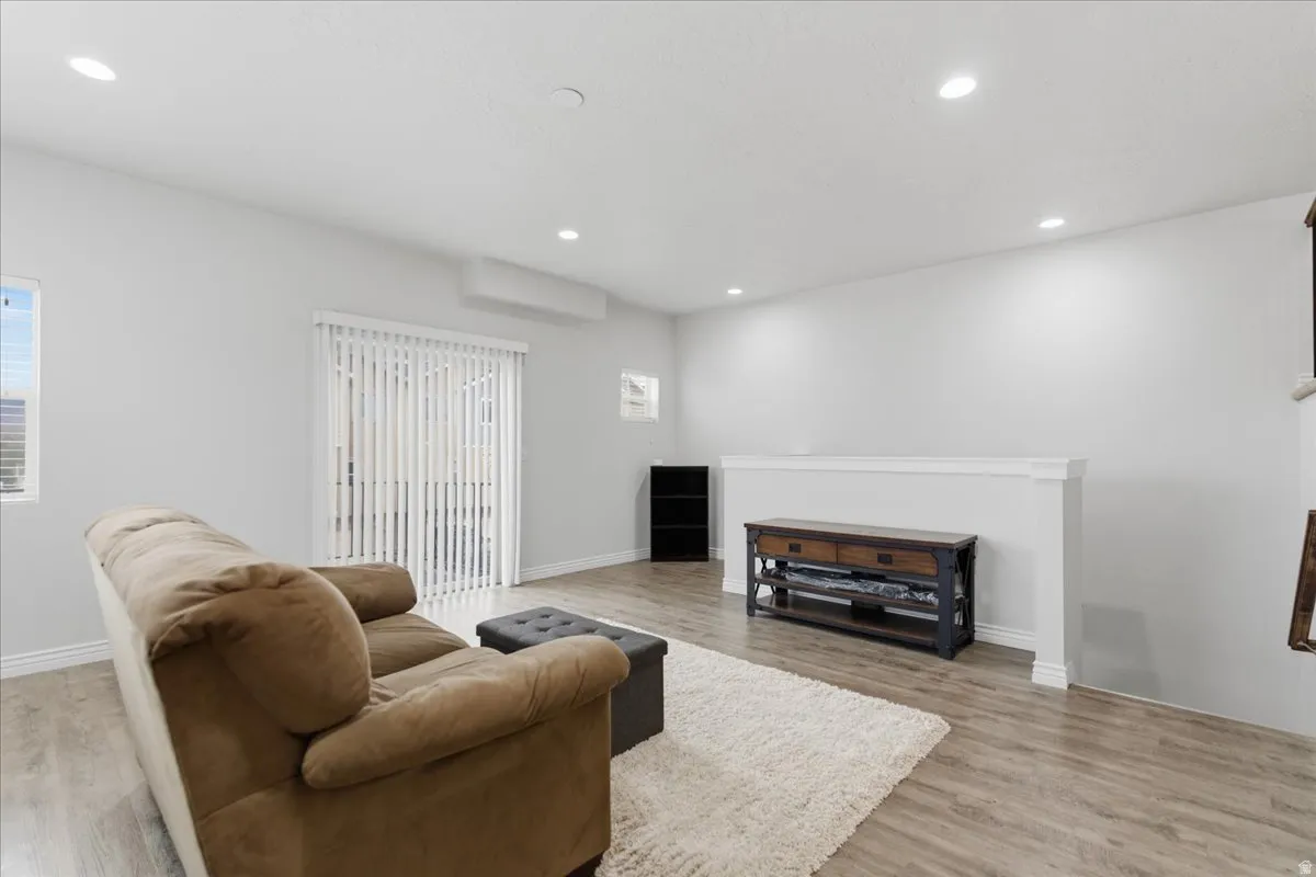 Bright interior with wood-finish flooring, white walls, and recessed lighting