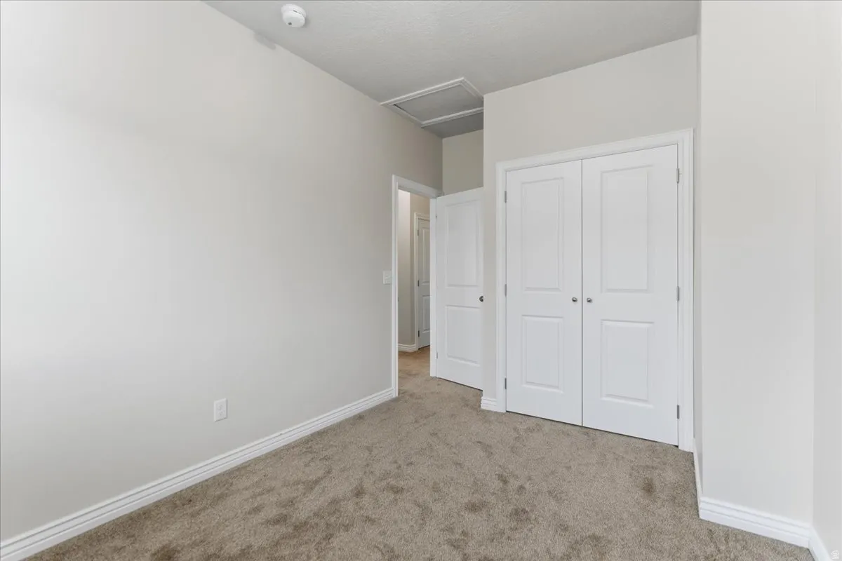 Neutral-toned carpet flooring with white baseboards throughout