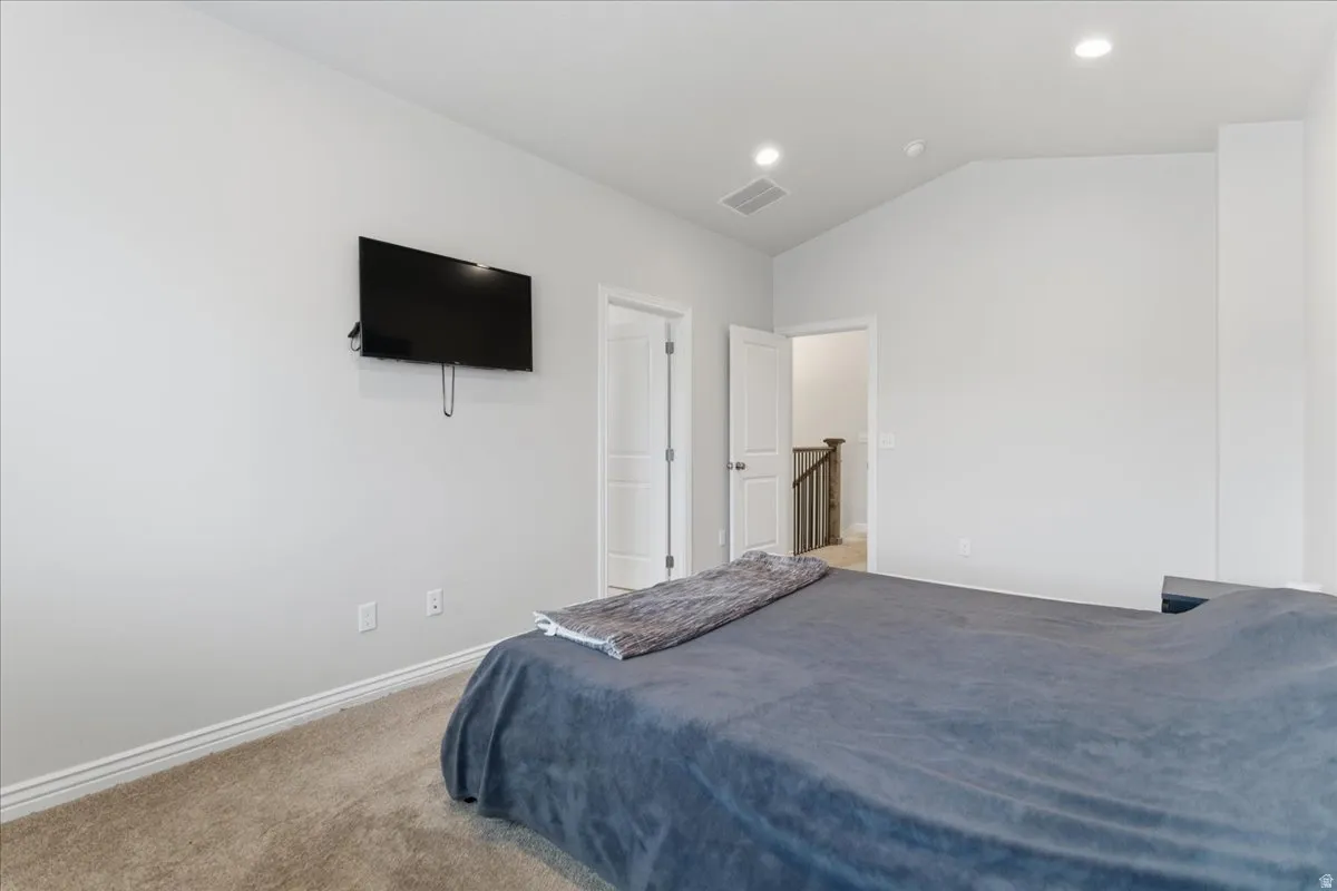 Carpeted room featuring a vaulted ceiling with recessed lighting