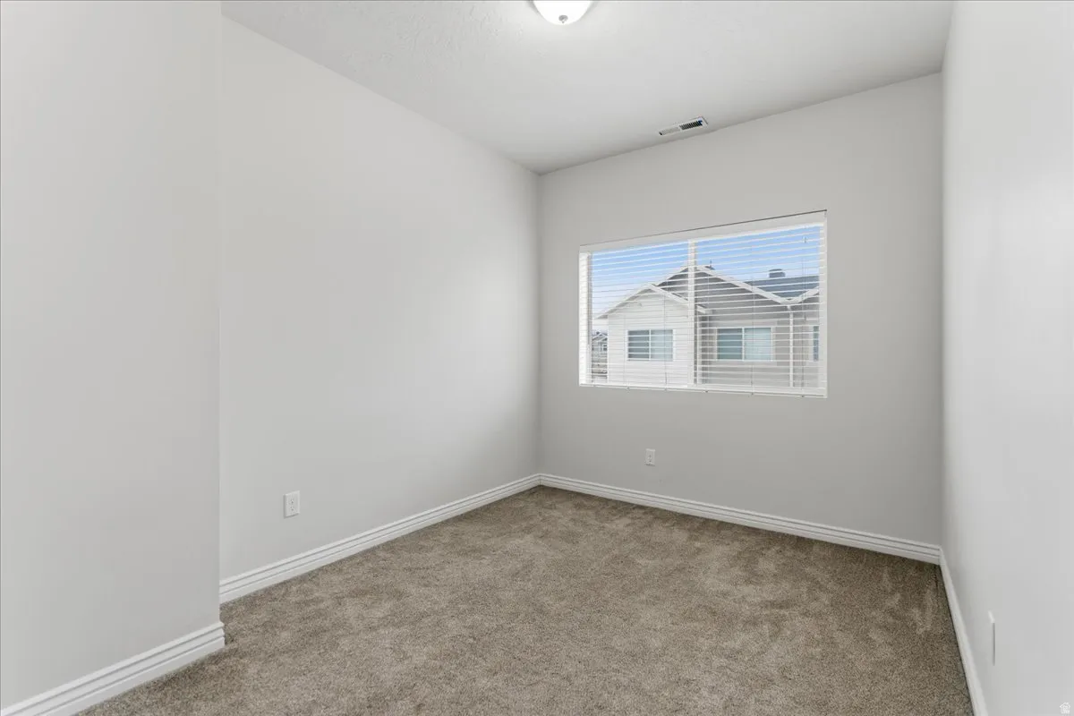 Room featuring neutral wall tones, textured carpeting, a recessed window with blinds, and white baseboards