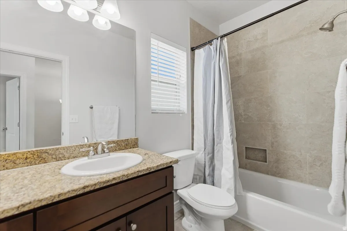 Bathroom featuring a spacious vanity with a granite-style countertop, undermount sink, and brushed nickel faucet