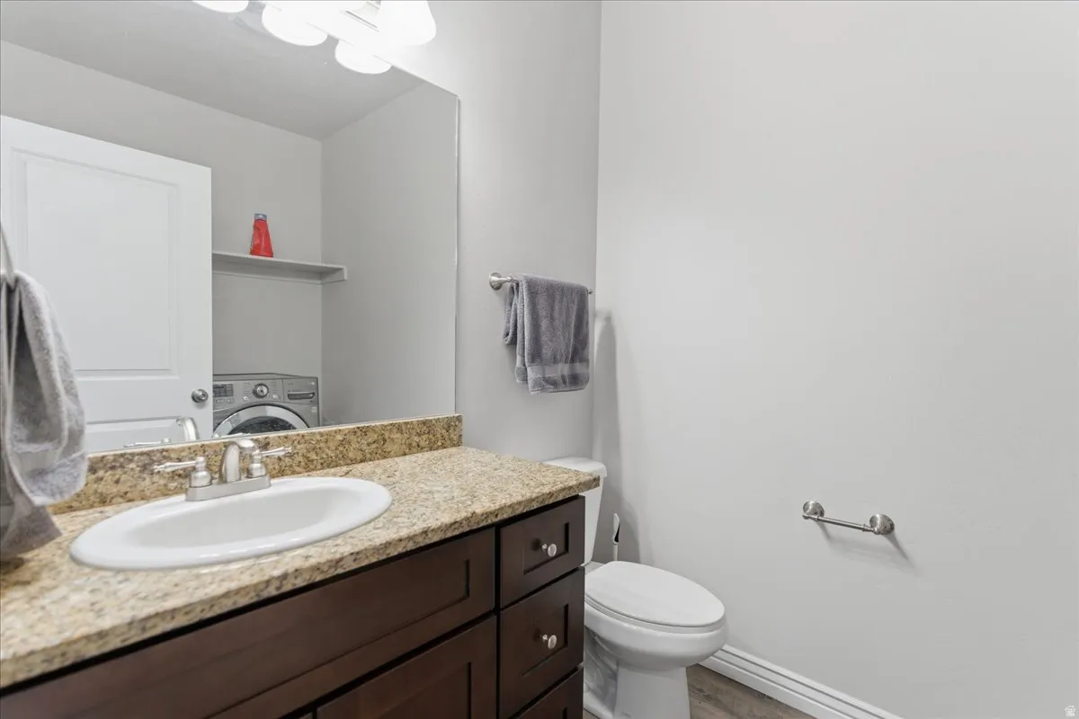 Vanity featuring an oval undermount sink with a chrome faucet, granite-style countertop, and dark wood cabinetry