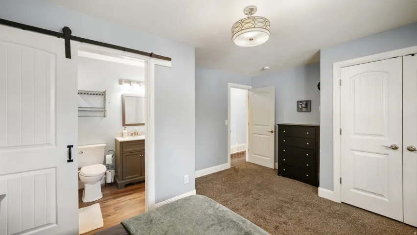 Bedroom featuring a white barn door entrance to a private bathroom
