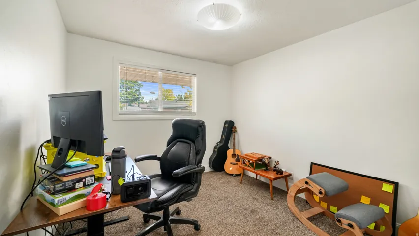 Third bedroom with a ceiling-mounted light fixture, a window featuring blinds & neutral carpeting