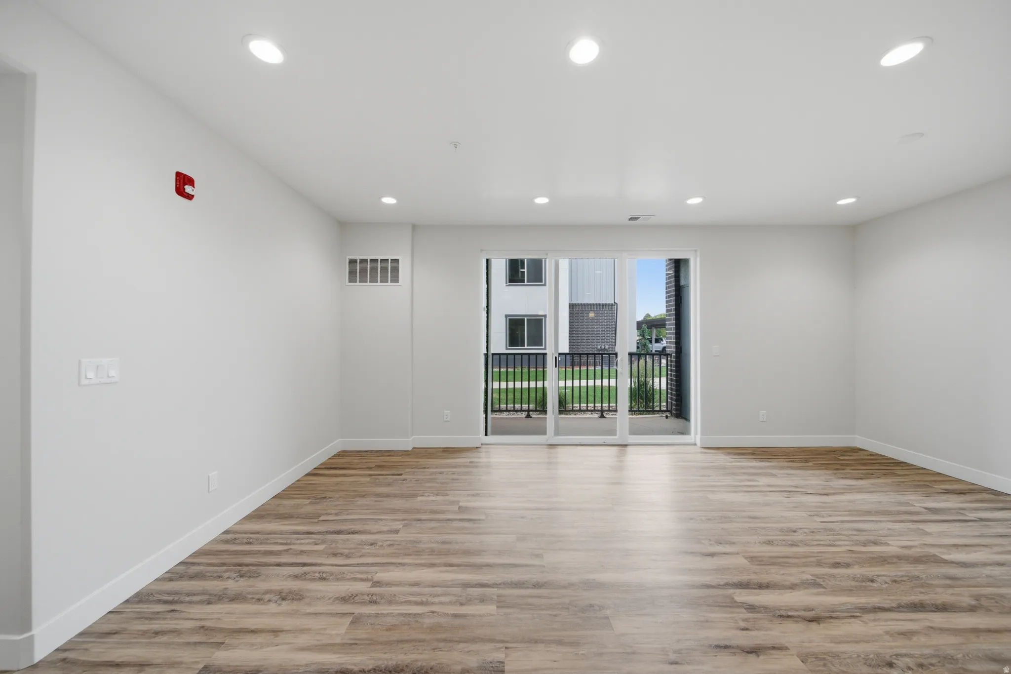 Bright, open room featuring wood-finish flooring, recessed lighting, and white baseboards