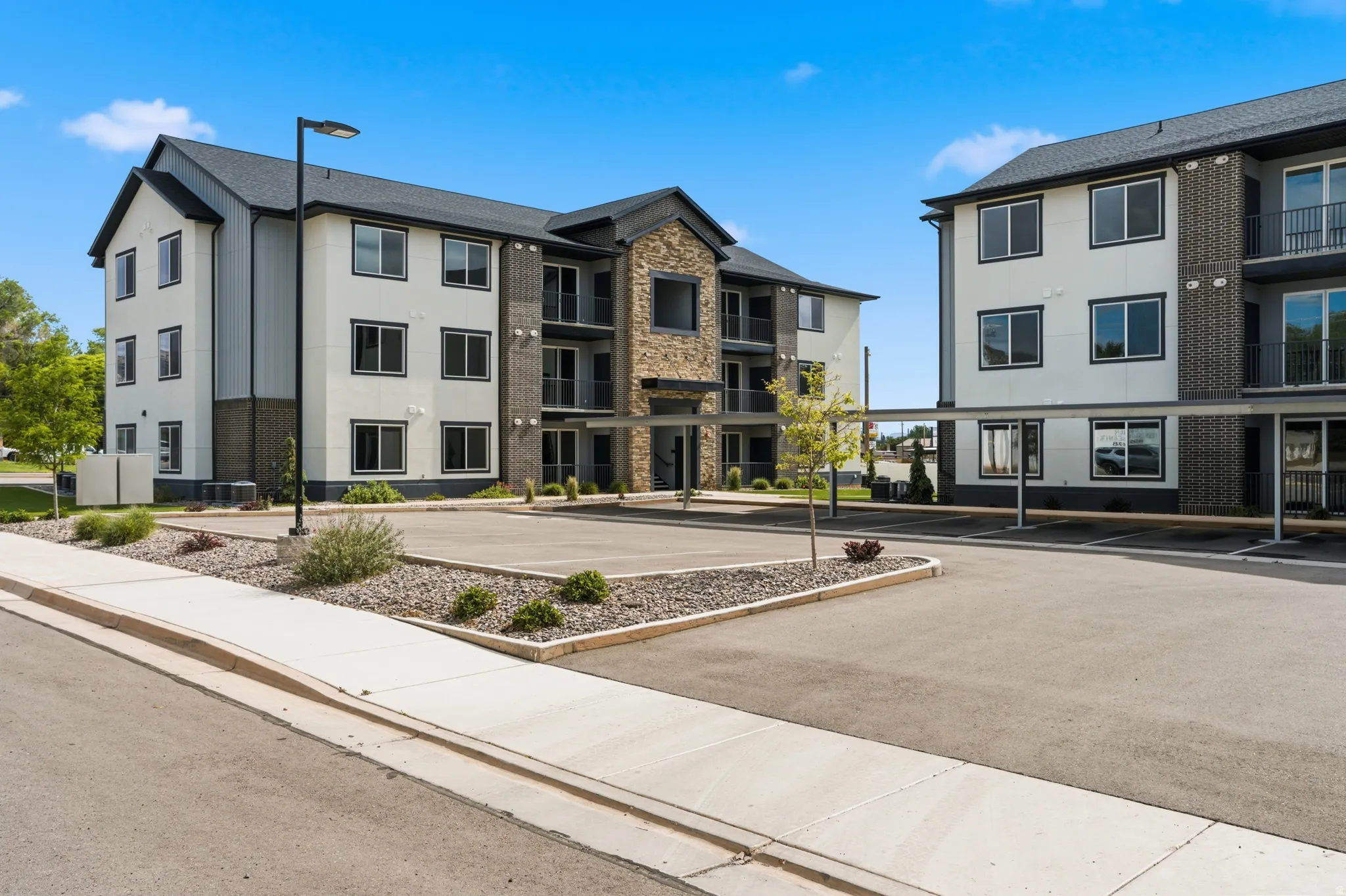 Contemporary multi-story building featuring a stone and siding exterior, private balconies, and covered parking
