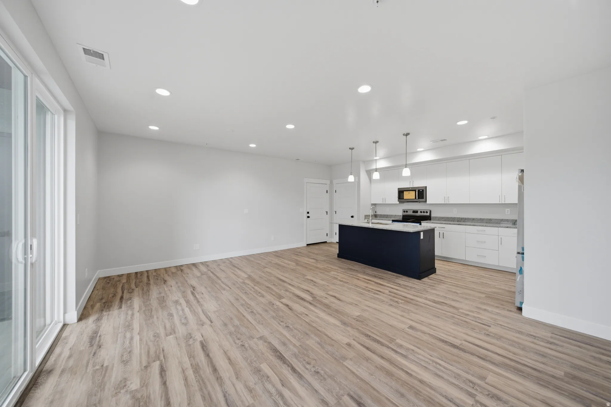Open-concept living space featuring wood-finish flooring, recessed lighting, and a sliding glass door