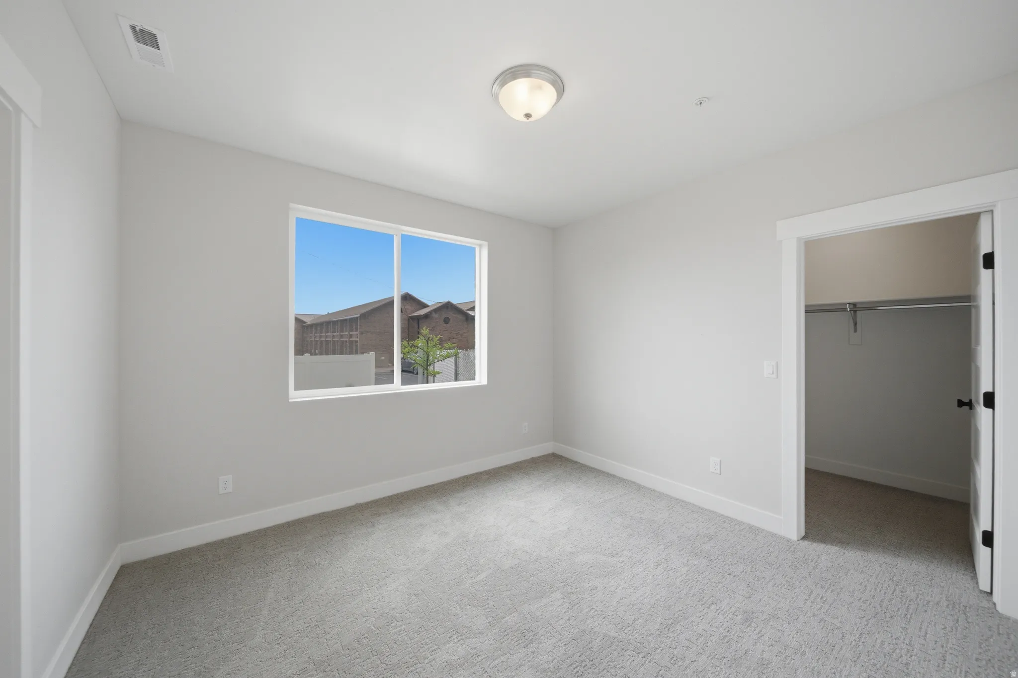 Carpeted room featuring a window, overhead flush-mount lighting, and a closet with a hanging rod